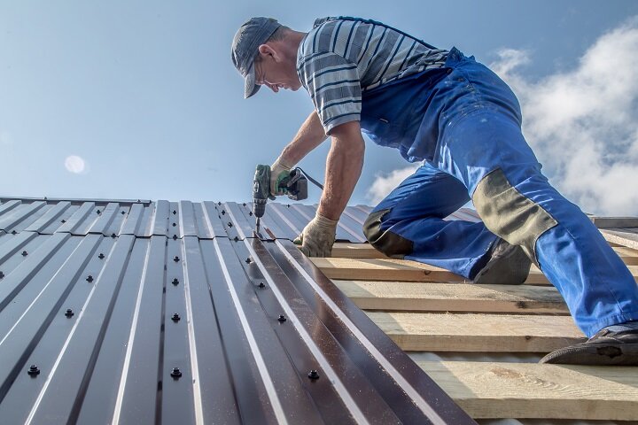 roofer on top of roof replacing metal sheets